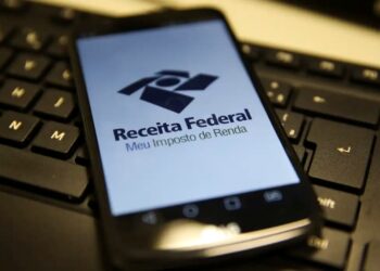 Aplicativo da Receita Federal exibindo Meu Imposto de Renda em um smartphone sobre um teclado.
