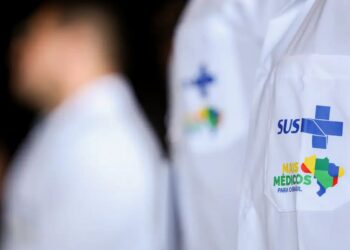 Médicos com jaleco do SUS, representando o programa Mais Médicos para o Brasil, enquanto o Enamed 2025 é realizado.