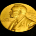 Medalha dourada do Prêmio Nobel mostrando o perfil de Alfred Nobel e inscrições em latim