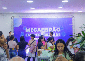 Pessoas jovens participando do Megafeirão de Empregabilidade em ambiente interno com painel púrpura ao fundo