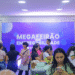 Pessoas jovens participando do Megafeirão de Empregabilidade em ambiente interno com painel púrpura ao fundo