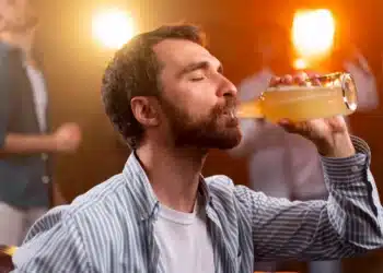 Homem bebendo uma garrafa, simbolizando os efeitos do consumo de metanol no corpo humano.