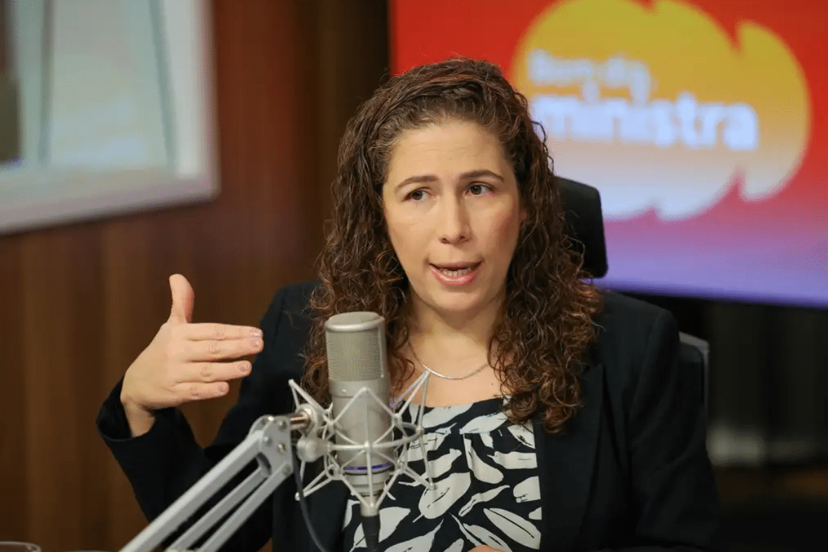 Mulher falando em microfone de estúdio durante entrevista em podcast.