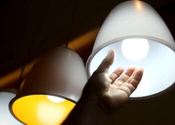 Mão tocando uma lâmpada branca, simbolizando a busca pela energia elétrica gratuita no Brasil.