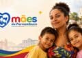 Mãe abraça dois filhos pequenos ao lado da marca do programa Mães de Pernambuco, que paga R$ 300 mensais