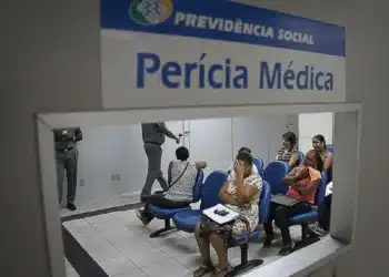 Pessoas aguardando atendimento para perícia médica no INSS, com sinalização indicativa de 'Perícia Médica'.
