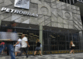 Fachada da Petrobras com pessoas caminhando em frente e grades de proteção na entrada