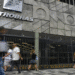 Fachada da Petrobras com pessoas caminhando em frente e grades de proteção na entrada