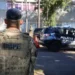 Agente da tropa com uniforme camuflado de costas próximo a viaturas da Polícia Penal Federal em operação