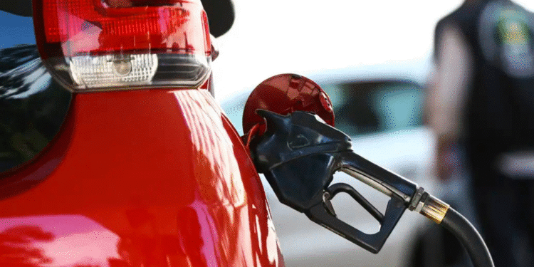 Carro vermelho sendo abastecido com bomba de combustível preta em posto de gasolina