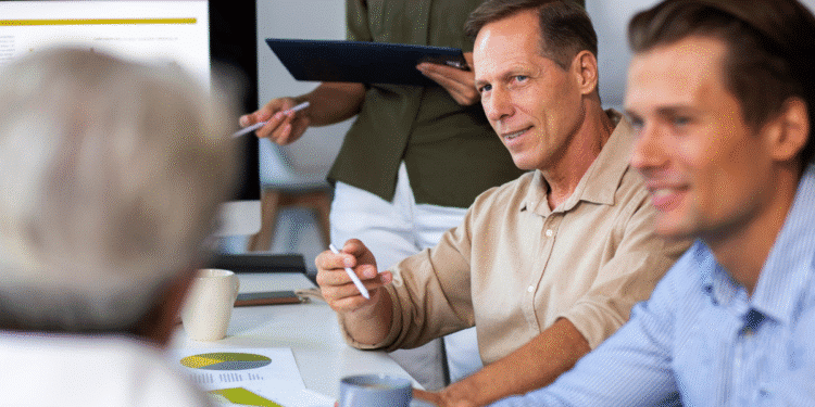 Homens e uma mulher em reunião de negócios com gráficos e computador no escritório