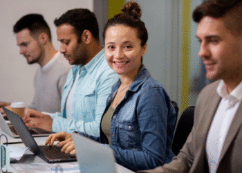 Quatro pessoas concentradas usando laptops em ambiente de trabalho colaborativo