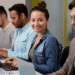 Quatro pessoas concentradas usando laptops em ambiente de trabalho colaborativo