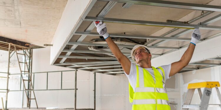 Trabalhador de construção civil ajustando estrutura de teto durante obra, com colete de segurança e capacete, ilustrando o Programa Reforma Casa Brasil.