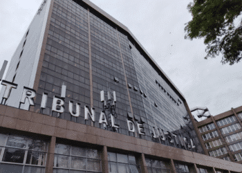 Edifício do Tribunal de Justiça com fachada de vidro refletivo e céu nublado ao fundo