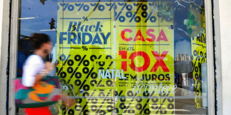 Fachada de loja com vitrines decoradas para Black Friday, adesivos de promoções e pessoa passando em frente