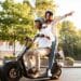 Casal usando scooter elétrica com capacetes em via pública representando nova legislação de ciclomotores 2026