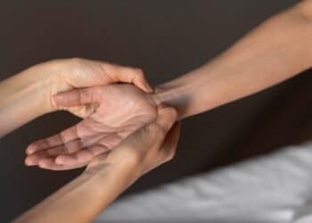Pessoa examinando pulso e antebraço de outra para verificar presença de músculo palmar longo
