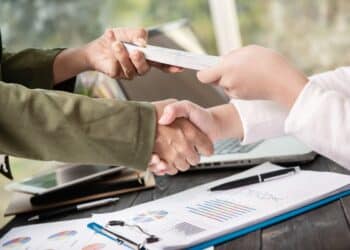 Acordo de renegociação sendo fechado com aperto de mãos e documentos do Feirão Limpa Nome