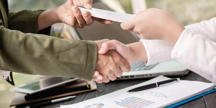 Acordo de renegociação sendo fechado com aperto de mãos e documentos do Feirão Limpa Nome