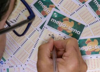 Apostador preenchendo múltiplos volantes da Mega-Sena com caneta para concorrer ao sorteio do feriado