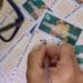 Apostador preenchendo múltiplos volantes da Mega-Sena com caneta para concorrer ao sorteio do feriado
