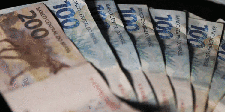 Cédulas de dinheiro em leque representando a primeira parcela do 13º salário depositada na conta.