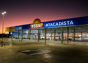 Fachada de uma unidade do Assaí Atacadista ao entardecer, com estacionamento amplo e iluminação externa.