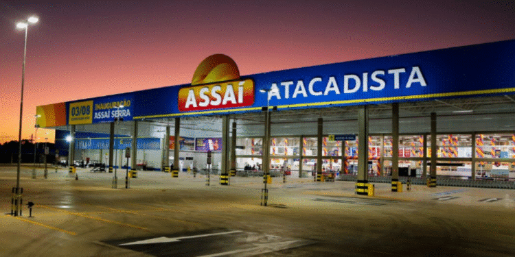 Fachada de uma unidade do Assaí Atacadista ao entardecer, com estacionamento amplo e iluminação externa.