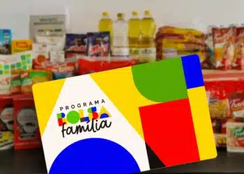 Cartão do Programa Bolsa Família 2026 em frente a alimentos básicos, como óleos, massas e arroz, simbolizando o apoio a famílias de baixa renda.