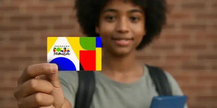Criança segurando o cartão do programa Bolsa Família, com fundo de tijolos, representando os pagamentos do benefício de novembro.