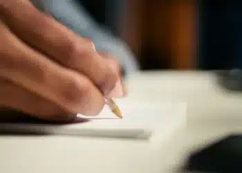 Pessoa escrevendo em um caderno, representando preparação para a prova discursiva do CNU 2025.