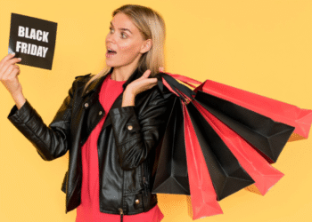 Mulher segurando sacolas de compras e um cartão escrito Black Friday sobre fundo amarelo.