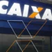 Imagem da fachada da agência da CAIXA Econômica Federal com o logotipo iluminado e visível.