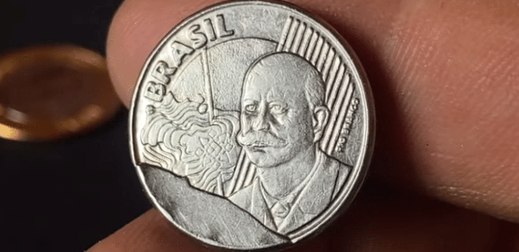 Close-up do anverso de uma moeda brasileira de 50 centavos ano 2002, com a imagem de Barão do Rio Branco, destacando o defeito de cunho quebrado (erro de fabricação) que a torna rara e valiosa.
