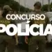 Imagem de dois policiais militares de costas ao lado de um carro da Polícia Militar, com destaque para a inscrição 'CONCURSO POLÍCIA'.