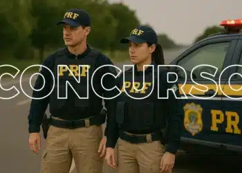 Dois agentes da Polícia Rodoviária Federal em uniforme, posando ao lado de um carro da PRF em uma estrada.