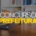 Texto "Concurso Prefeitura" em amarelo e branco sobre mesa com laptop e estante de livros ao fundo.