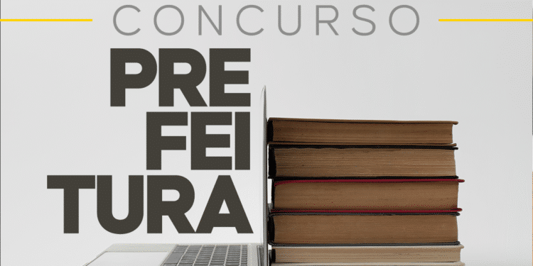 Notebook aberto encostado em pilha de livros com palavra concurso prefeitura ao lado.