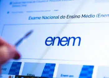 Tela de computador exibindo site oficial do Enem com pessoa indicando a tela com uma caneta