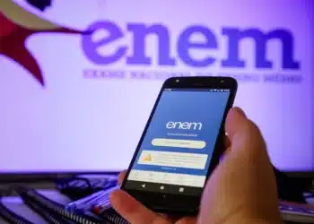 Pessoa segurando celular com aplicativo do ENEM aberto na tela azul