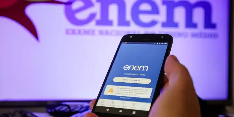 Pessoa segurando celular com aplicativo do ENEM aberto na tela azul