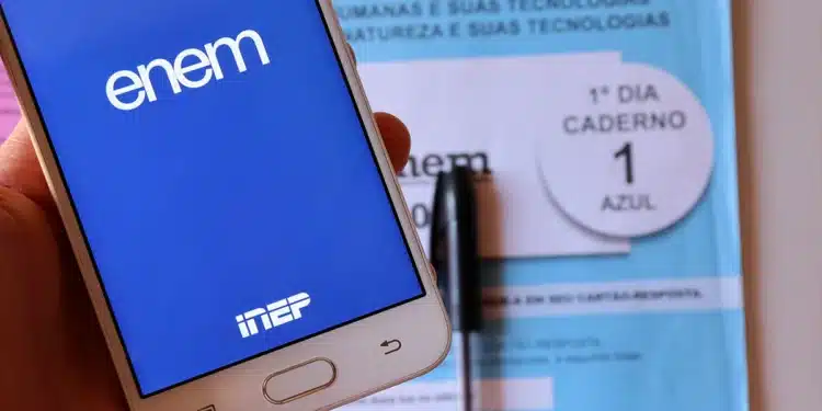 Celular com aplicativo do Enem aberto e caderno azul do primeiro dia do exame com caneta