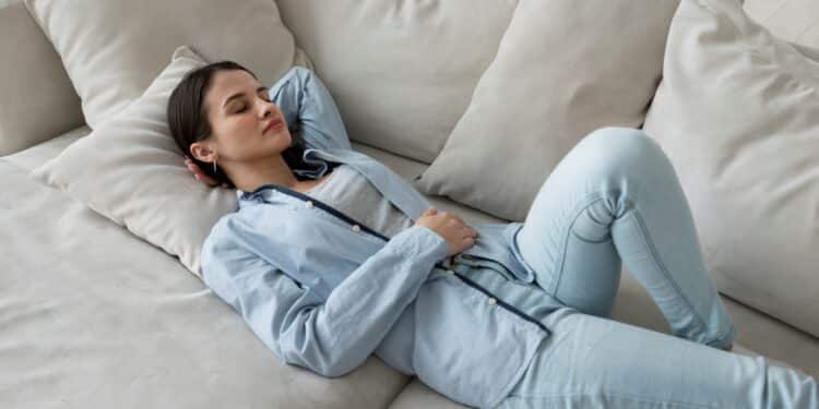Mulher descansando no sofá, com uma expressão tranquila, simbolizando momentos de pausa que podem se tornar frequentes com os feriados de 2026.