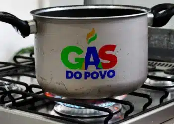Panela com logo do programa Gás do Povo em cima de um fogão, com gás aceso, representando o benefício do vale de gás para a população.