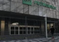 Fachada da Petrobras em concreto com grade de metal e homem caminhando com roupa preta