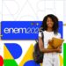 Estudante sorridente com mochila e caderno à frente do logotipo do Enem 2025.