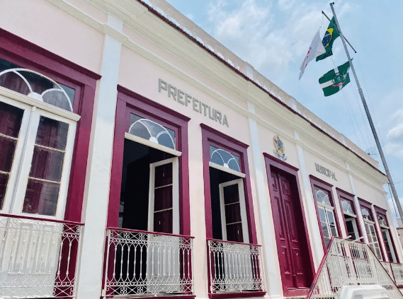 Prefeitura de Leopoldina–MG encerra inscrições de edital Fachada do prédio da Prefeitura de Leopoldina, em Minas Gerais, com bandeiras hasteadas.