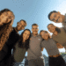 Grupo de jovens aprendizes e colaboradores da Raízen sorrindo em ambiente corporativo.