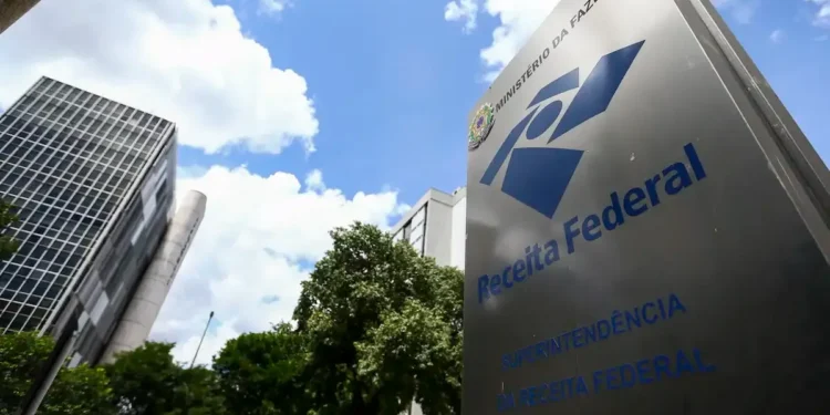 Placa da Receita Federal, órgão do Ministério da Fazenda do Brasil, com edifício ao fundo.